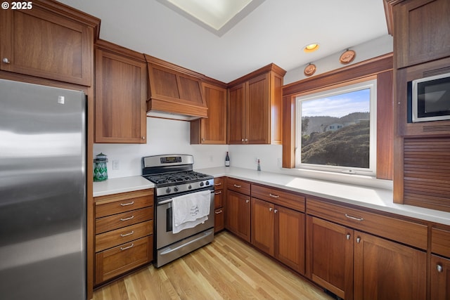 93885 Boulder Pl, Gold Beach, OR 97444 - kitchen with light wood-style flooring, stainless steel appliances, custom exhaust hood, brown cabinets, and light countertops