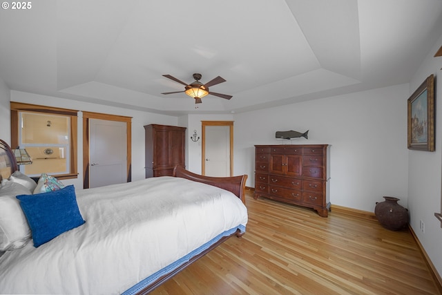 93885 Boulder Pl, Gold Beach, OR 97444 - bedroom with a tray ceiling, baseboards, light wood-type flooring, and a ceiling fan