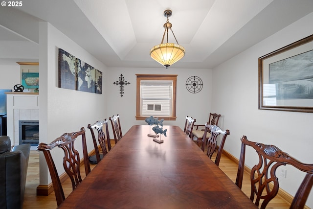 93885 Boulder Pl, Gold Beach, OR 97444 - dining area with a tray ceiling, a fireplace, baseboards, and wood finished floors