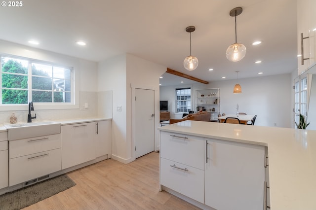 kitchen featuring a sink, light wood-type flooring, white cabinets, light countertops, and recessed lighting