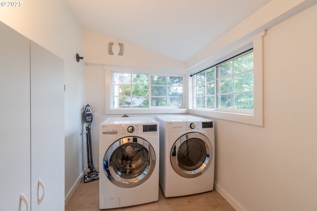 laundry room featuring washer and clothes dryer, healthy amount of natural light, light wood-style floors, and baseboards
