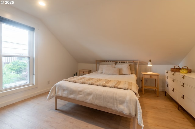 bedroom with vaulted ceiling, light wood-style flooring, and baseboards