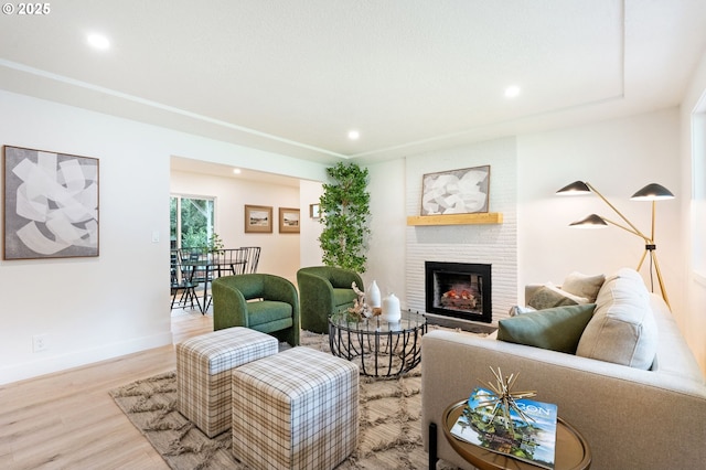 living room featuring wood finished floors, a fireplace, recessed lighting, and baseboards