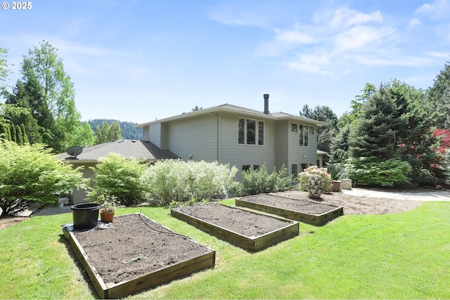 back of property featuring a vegetable garden and a lawn