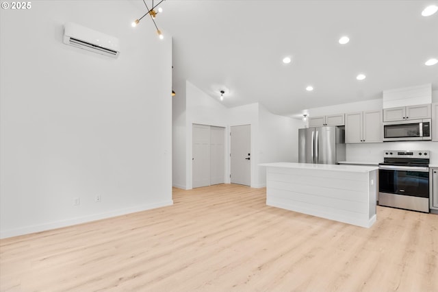 kitchen featuring lofted ceiling, a wall mounted AC, a center island, light wood-type flooring, and stainless steel appliances