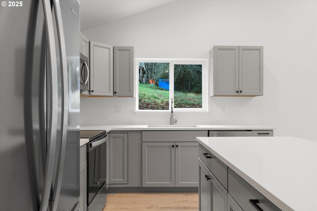 kitchen featuring lofted ceiling, light hardwood / wood-style flooring, refrigerator, gray cabinetry, and electric range oven