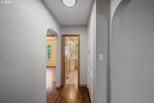 2111 Greenwood Ave, Reedsport, OR 97467 - hallway with arched walkways, dark wood-style flooring, baseboards, and a textured wall