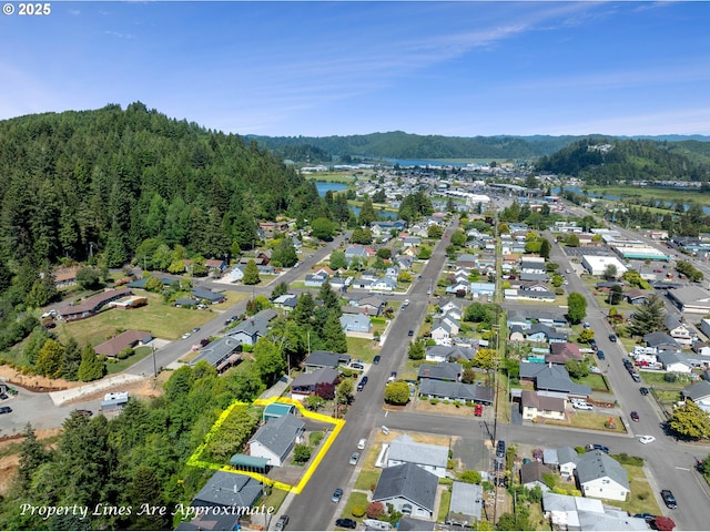 2111 Greenwood Ave, Reedsport, OR 97467 - aerial perspective of suburban area featuring a large body of water, a heavily wooded area, and property boundaries highlighted
