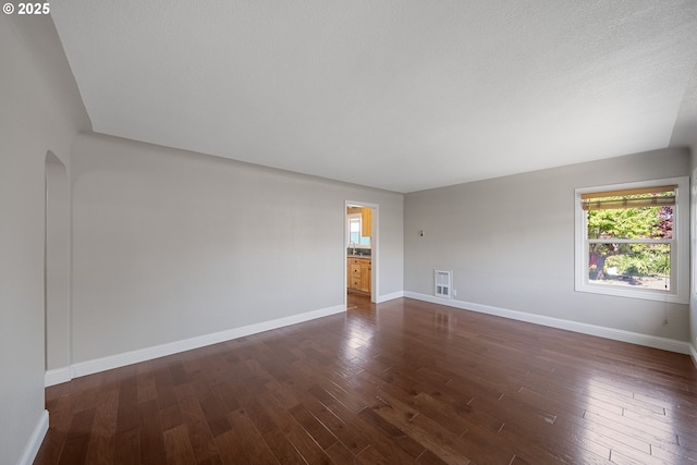 2111 Greenwood Ave, Reedsport, OR 97467 - unfurnished room with dark wood-style floors, baseboards, and arched walkways