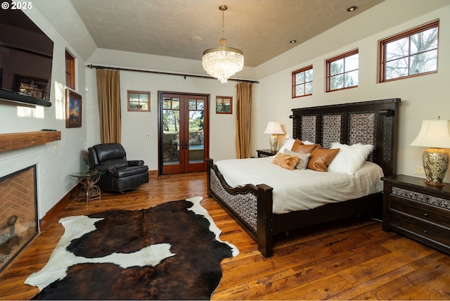 23021 Brushline Ct, Bend, OR 97701 - bedroom featuring access to outside, wood finished floors, a fireplace, french doors, and a chandelier