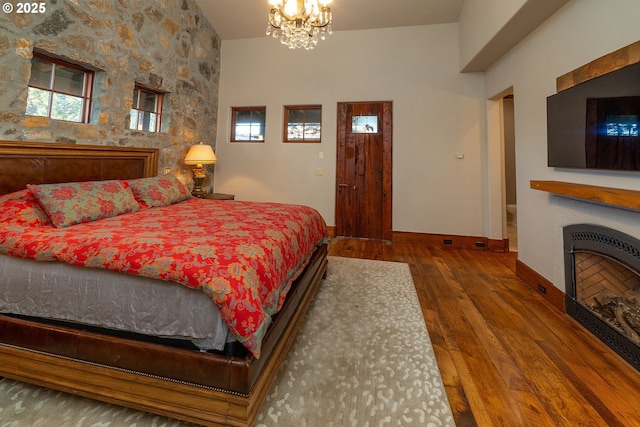 23021 Brushline Ct, Bend, OR 97701 - bedroom with wood-type flooring, a fireplace, and a chandelier
