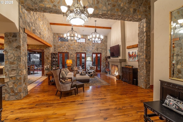 23021 Brushline Ct, Bend, OR 97701 - living area with a chandelier, hardwood / wood-style flooring, a towering ceiling, beam ceiling, and a fireplace