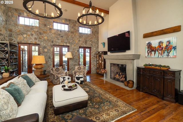 23021 Brushline Ct, Bend, OR 97701 - living room with a chandelier, french doors, a fireplace with flush hearth, a high ceiling, and beamed ceiling