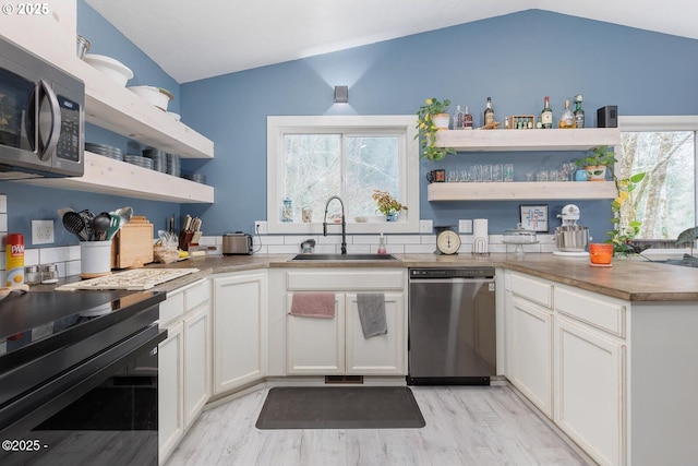 kitchen with lofted ceiling, sink, white cabinets, and appliances with stainless steel finishes