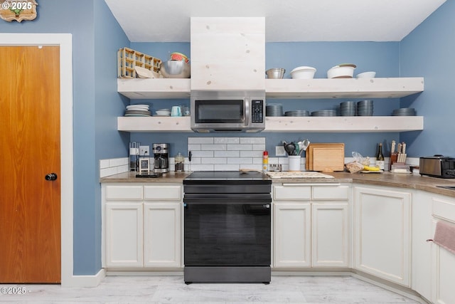 kitchen featuring white cabinetry, black electric range, and decorative backsplash