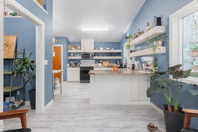 kitchen featuring white cabinetry, decorative backsplash, stove, kitchen peninsula, and light hardwood / wood-style flooring