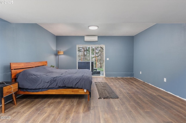 bedroom with wood-type flooring, access to outside, and an AC wall unit