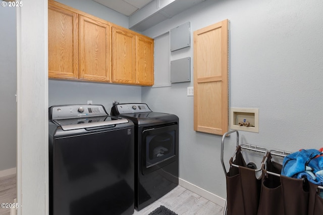 laundry room featuring independent washer and dryer, cabinets, and light wood-type flooring