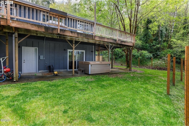 rear view of house featuring a hot tub, a wooden deck, and a yard