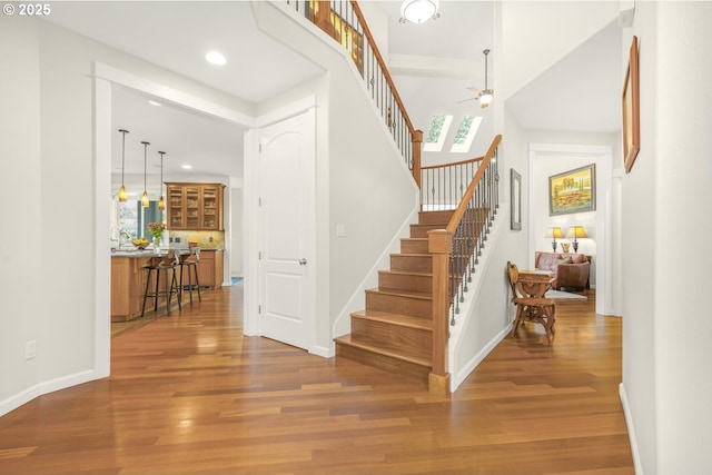 entryway featuring baseboards, ceiling fan, stairway, and wood finished floors