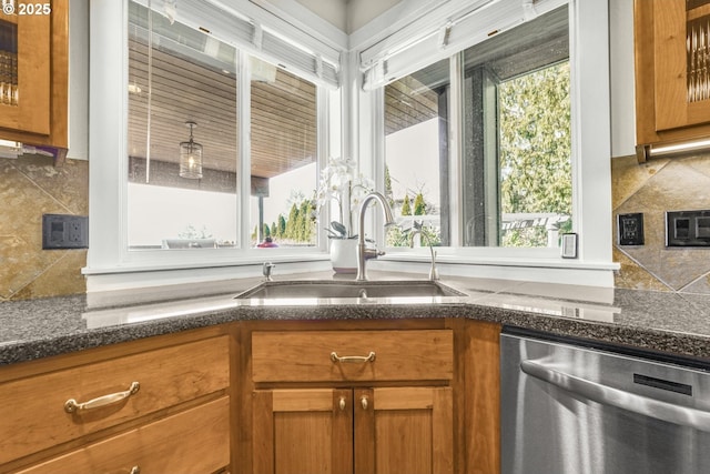 kitchen featuring stainless steel dishwasher, brown cabinetry, a sink, and decorative backsplash