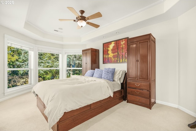 bedroom with light carpet, a raised ceiling, and baseboards