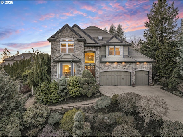 view of front facade featuring an attached garage, driveway, and stone siding