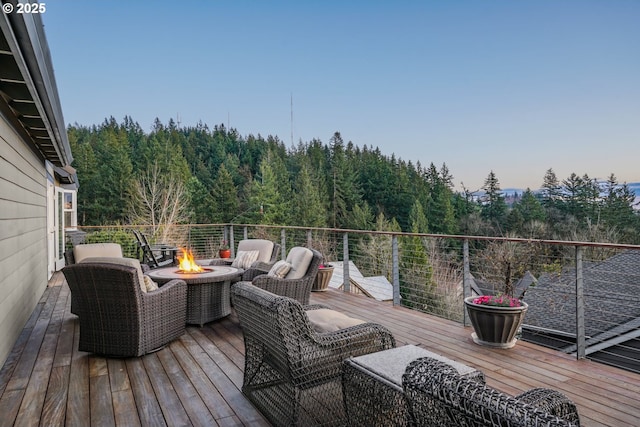 deck featuring an outdoor fire pit and a view of trees