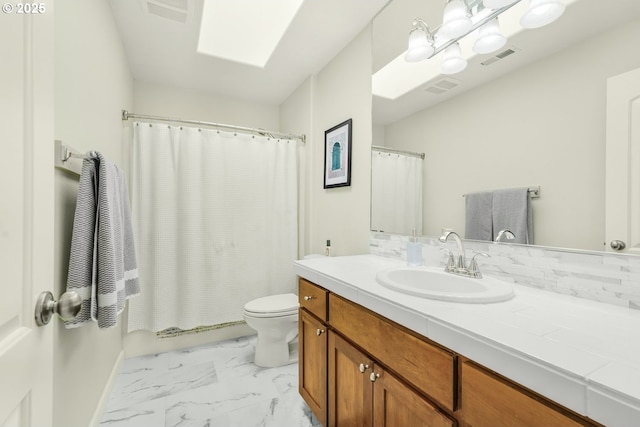 bathroom featuring toilet, a skylight, visible vents, vanity, and marble finish floor