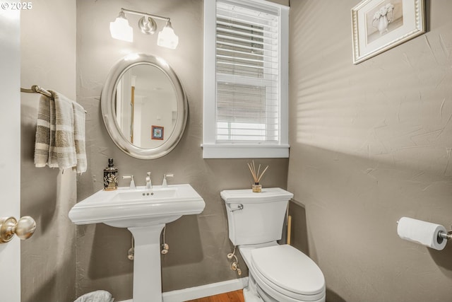 half bath featuring toilet and baseboards