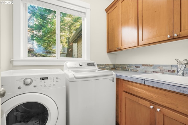 clothes washing area with washing machine and dryer, a sink, and cabinet space