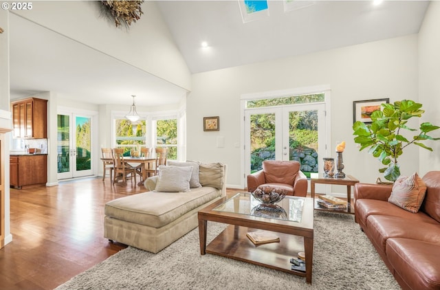 living area with high vaulted ceiling, french doors, and wood finished floors