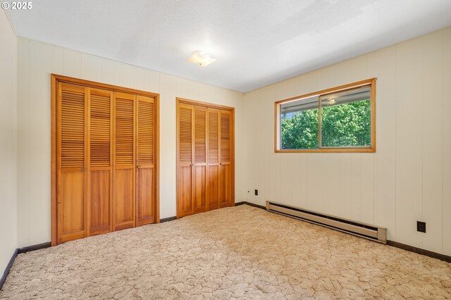 8095 Bewley St, Bay City, OR 97107 - unfurnished bedroom with a baseboard radiator, carpet flooring, two closets, and baseboards