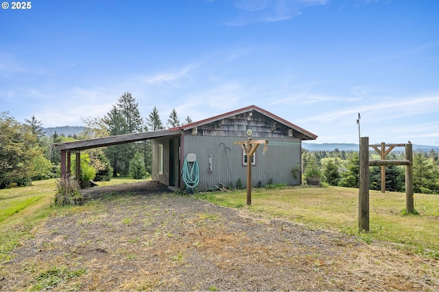 8095 Bewley St, Bay City, OR 97107 - view of home's exterior with an attached carport, an outdoor structure, an outbuilding, a mountain view, and a yard