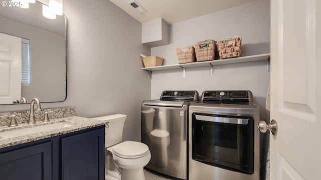 laundry area with laundry area, visible vents, washer and dryer, and a sink