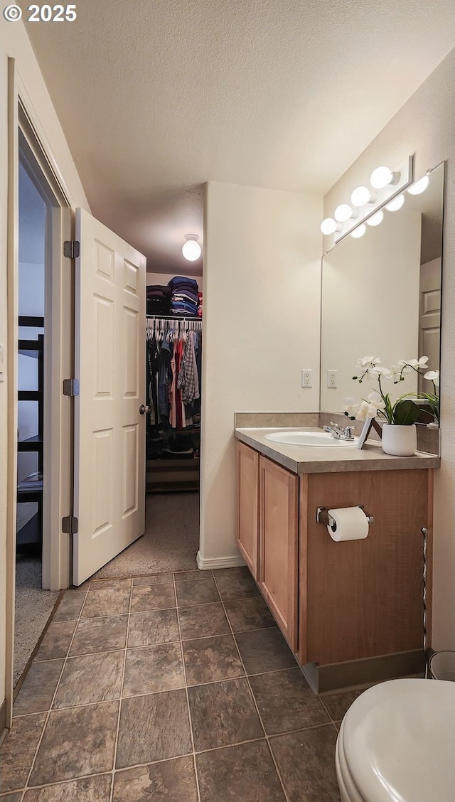 bathroom with a walk in closet, a textured ceiling, and vanity