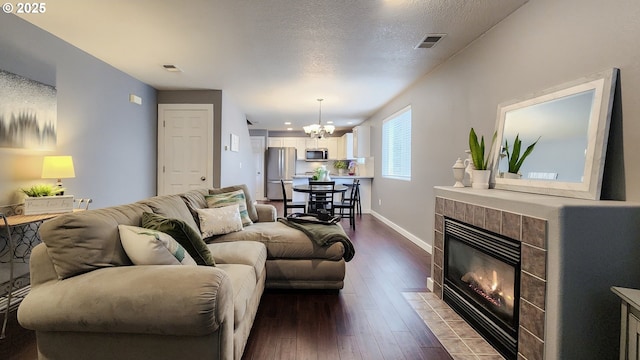 living area with dark wood-style floors, a fireplace, visible vents, a textured ceiling, and baseboards