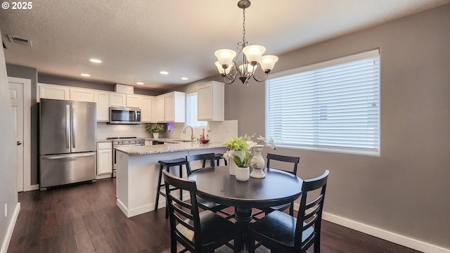 dining area with a textured ceiling, dark wood-style flooring, visible vents, and baseboards