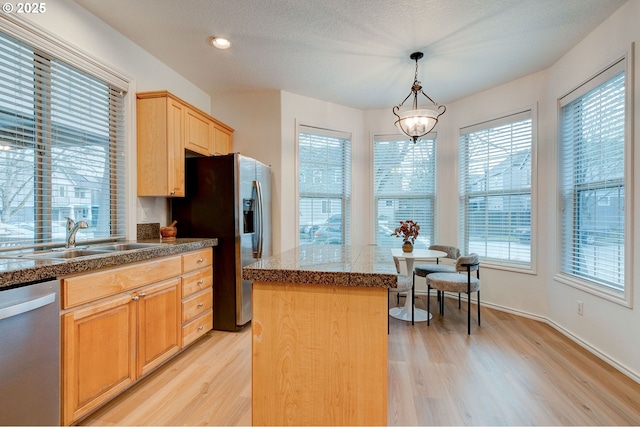 kitchen featuring pendant lighting, sink, a center island, stainless steel appliances, and light hardwood / wood-style flooring