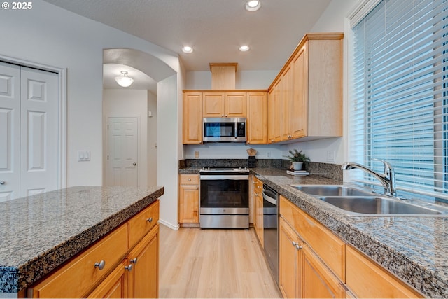 kitchen featuring sink, light hardwood / wood-style flooring, stainless steel appliances, a center island, and light brown cabinets