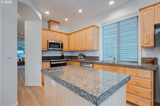 kitchen featuring appliances with stainless steel finishes, a center island, sink, and light brown cabinetry