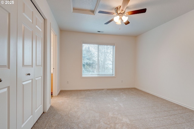 unfurnished bedroom with ceiling fan, light carpet, a textured ceiling, and a closet