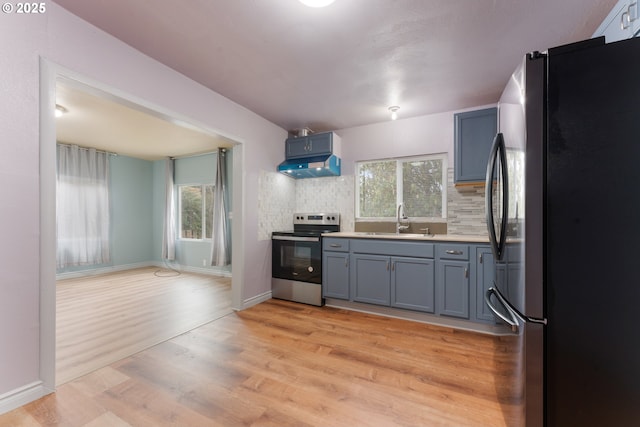 kitchen featuring light wood finished floors, light countertops, appliances with stainless steel finishes, a sink, and under cabinet range hood