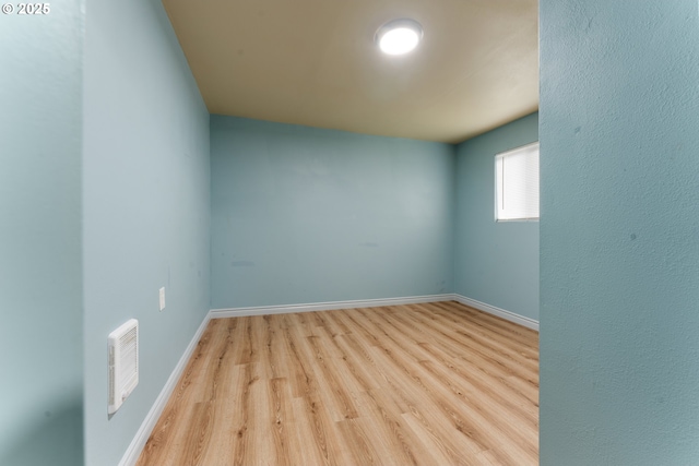 spare room with light wood-type flooring, visible vents, and baseboards