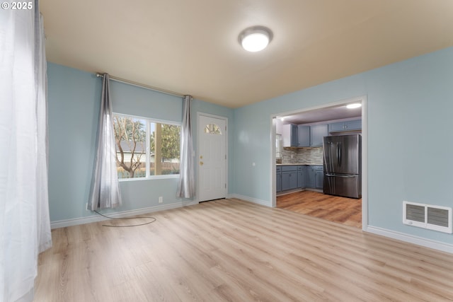 unfurnished living room with light wood finished floors, baseboards, and visible vents