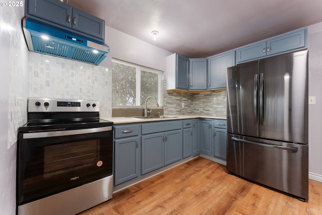 kitchen with blue cabinets, a sink, light countertops, appliances with stainless steel finishes, and ventilation hood