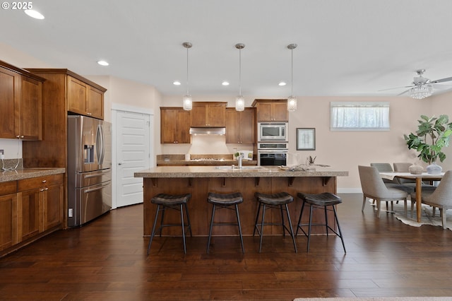 14609 NE 112th St, Vancouver, WA 98682 - kitchen with appliances with stainless steel finishes, under cabinet range hood, brown cabinetry, a breakfast bar, and recessed lighting