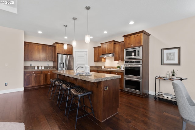 14609 NE 112th St, Vancouver, WA 98682 - kitchen with stainless steel appliances, under cabinet range hood, a kitchen breakfast bar, dark wood-style floors, and an island with sink