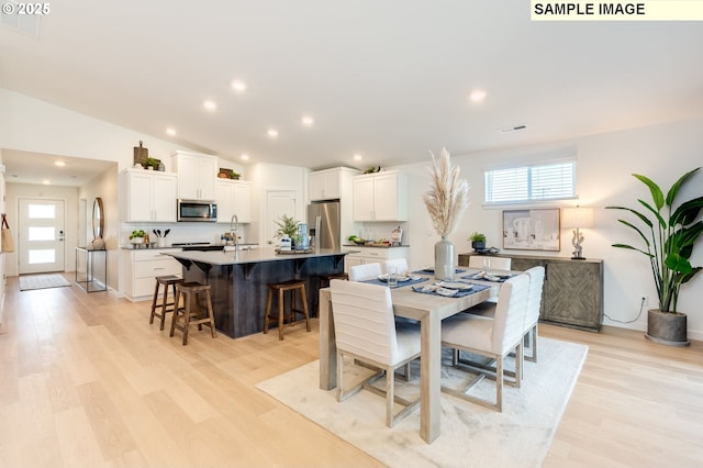 dining space featuring lofted ceiling, visible vents, light wood finished floors, and recessed lighting