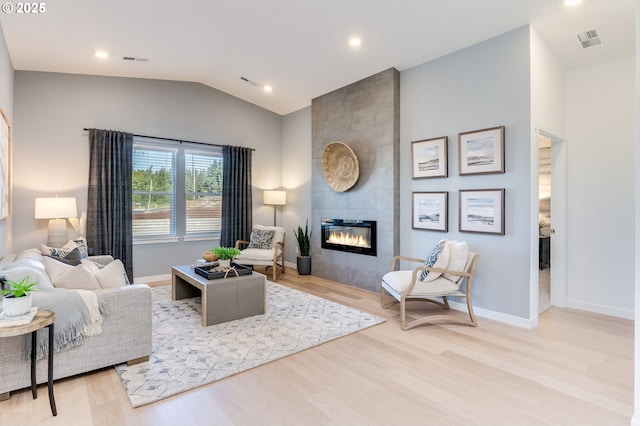 living room with lofted ceiling, a fireplace, wood finished floors, and baseboards